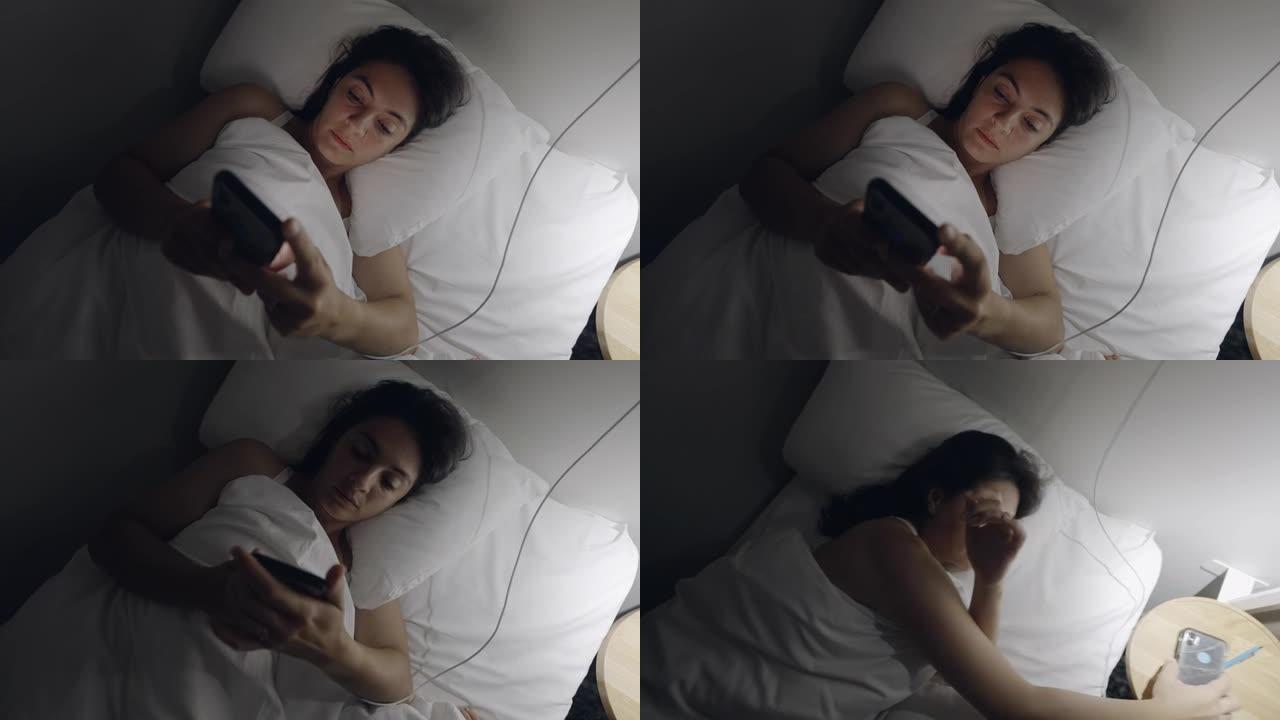 女人晚上躺在床上关掉手机。看着智能手机屏幕的女性关闭设备并关闭灯进入睡眠状态