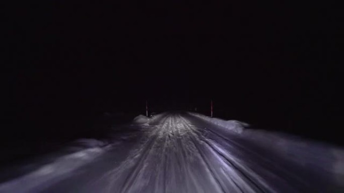 晚上在森林的雪路上开车。