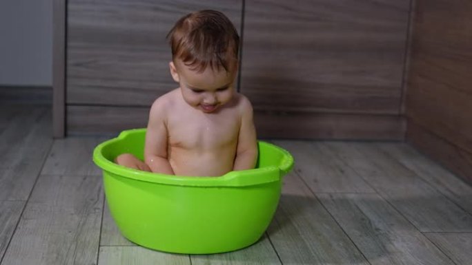 可爱的高加索小孩在洗碗里洗澡。快乐的宝宝在洗漱时玩水。
