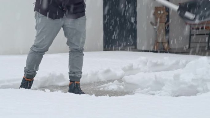 男子拿着铁锹清除车道上的积雪