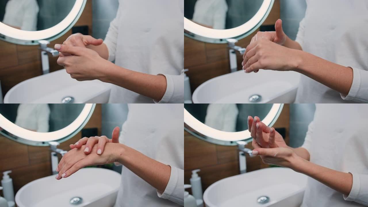 特写。无法辨认的女人在手掌中摩擦奶油或泡沫，站在现代浴室内部。美容，手部护理，水疗化妆品，美容概念。