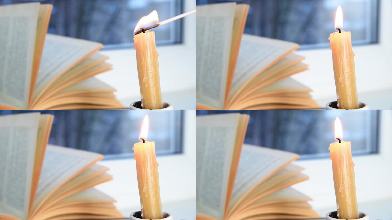 蜡烛燃烧和书在窗台上，冬天的早晨或傍晚，外面下雪，风在移动页面。选择性聚焦