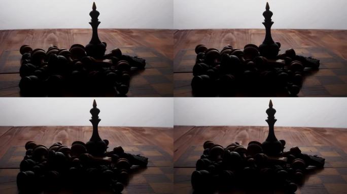 国际象棋棋子黑皇后站在棋盘上，周围是其他躺着的棋子。棋盘游戏。有点运动。摄像机沿着物体移动
