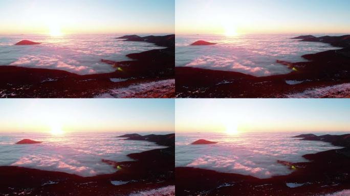 白雪皑皑山脊的空中无人机视图，日落之后的云层上方