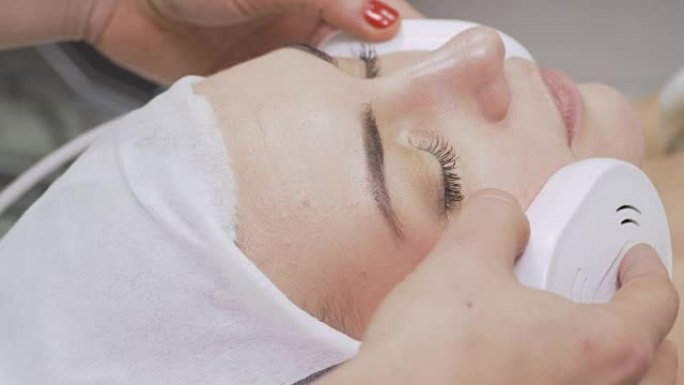 美容师在美容院中使用红外设备进行面部护理