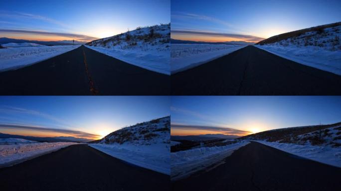 黄昏时在雪山路上驶向日落