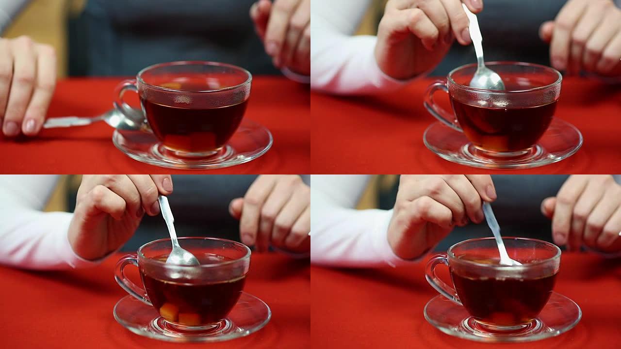 女人在杯子里搅拌精制糖，喝热红茶，