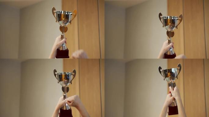 女人的手举起一个金奖杯。颁奖典礼、颁奖及胜利概念