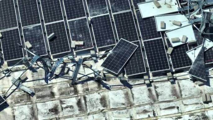安装在工业建筑屋顶上的飓风光伏太阳能电池板损坏的鸟瞰图，用于产生绿色生态电力。自然灾害的后果