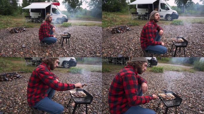 在露营车的背景下，穿着红色格子衬衫的男子在挪威河边烧烤