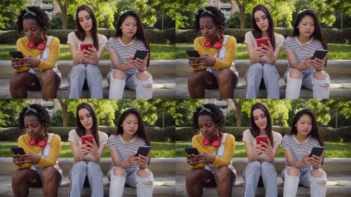 三个年轻严肃的女人在户外用手机。同事们在手机上看期末成绩。