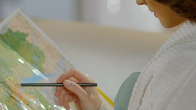 年轻女子拿着铅笔在地图上，计划旅行路线，度假