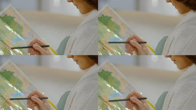 年轻女子拿着铅笔在地图上，计划旅行路线，度假