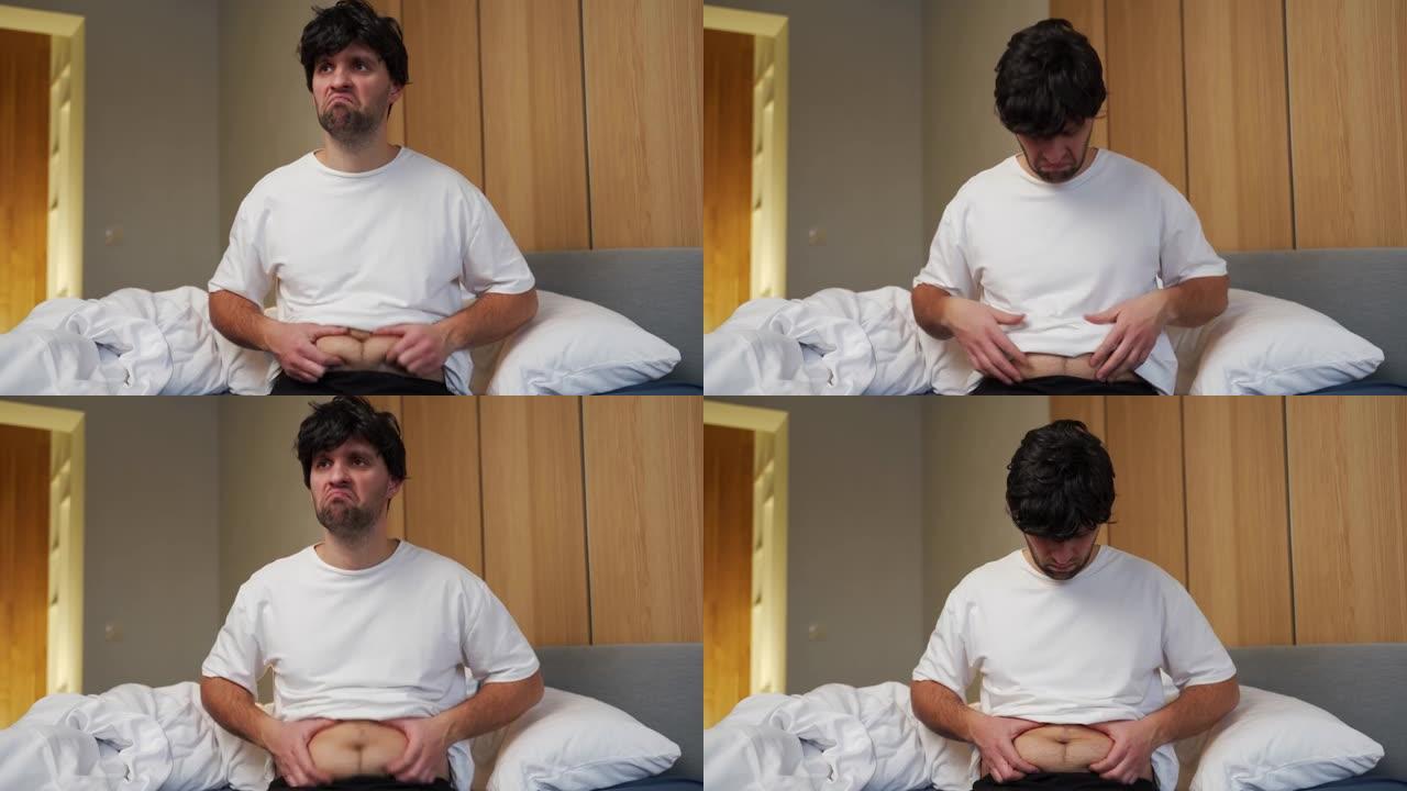 一个大肚子的胖子伸出肚子，坐在床上用手摸了一下。有患糖尿病风险的人，肥胖的糖尿病患者