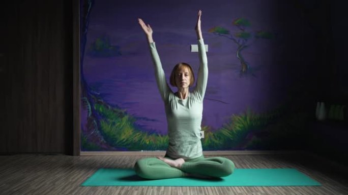 一个坐着的女人在紫色的墙壁上练习瑜伽的镜头