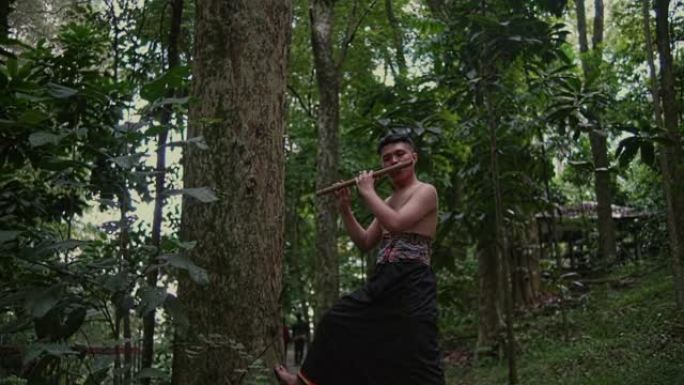 一个人在树附近大声吹奏竹笛