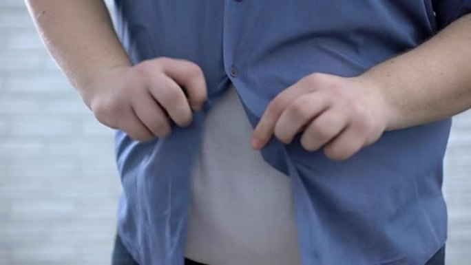肥胖男性扣蓝色衬衫，减肥过程，荷尔蒙紊乱
