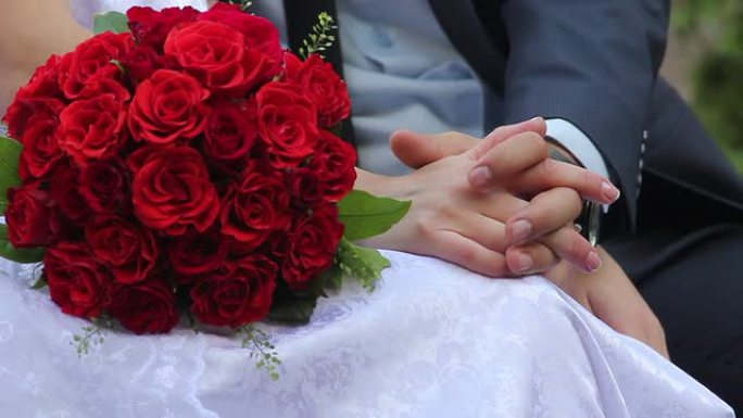 新婚夫妇新娘和新郎在长椅上捧着一束玫瑰花