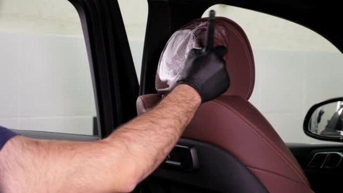 汽车服务人员用刷子和泡沫清洗汽车座椅的特写镜头。