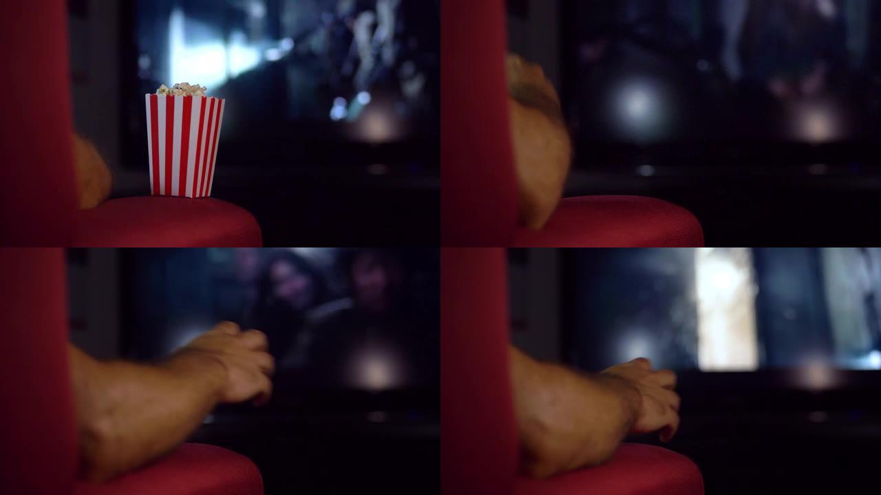 一名男子在看恐怖电影时惊恐地丢下爆米花。