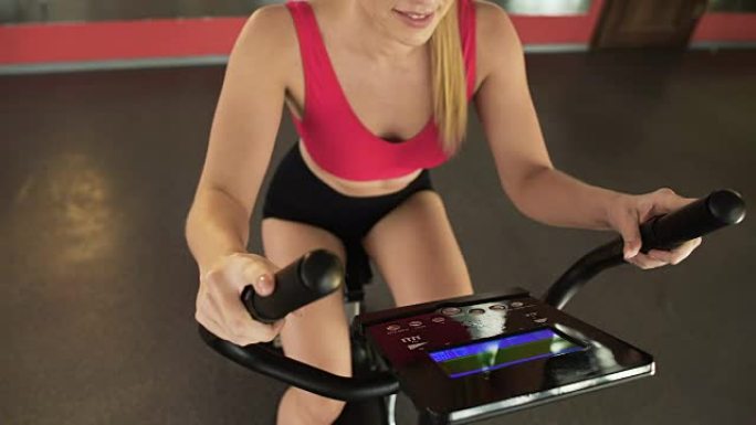 运动女子骑固定自行车，看着电子面板，运动