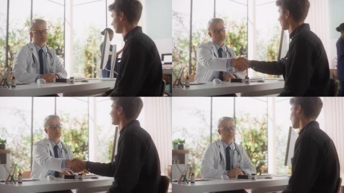 英俊的中年医生正在与一名男性患者交谈，在一家健康诊所咨询期间与他交谈。穿着白大褂的医生与一个年轻人握