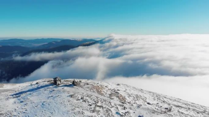 覆盖着雪，云和雾的山顶的空中无人机视图在下面滚动