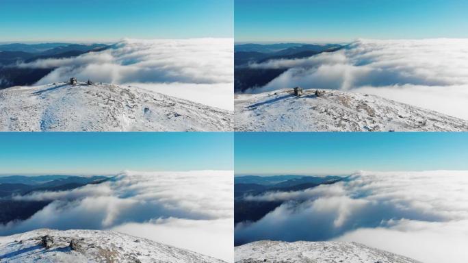 覆盖着雪，云和雾的山顶的空中无人机视图在下面滚动