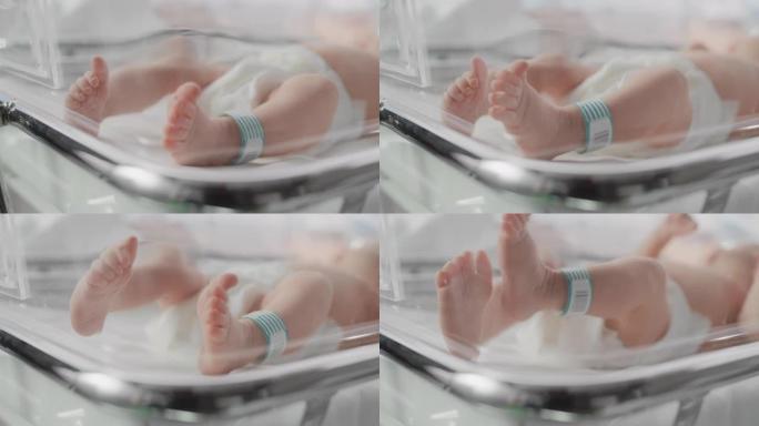 可爱的高加索新生婴儿躺在妇产医院的婴儿床里。一个小小的顽皮和精力充沛的孩子的肖像，腿上有名字ID标签
