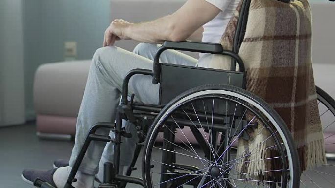 男性坐轮椅并触摸膝盖，令人沮丧的医学结论