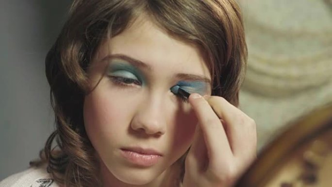 年轻的女学生用眼影画眼睛，第一次化妆，长大