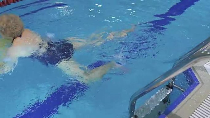 高级妇女用特殊设备在游泳池游泳