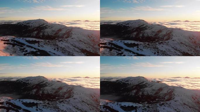 日落时白雪覆盖的山脉的空中无人机视图
