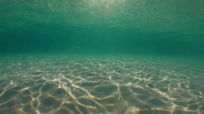 阳光穿透海水，带着柔和的波浪和运动，在沙滩上形成的水下光纹