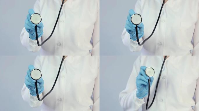 穿着实验室外套和医用手套的医生伸出听诊器