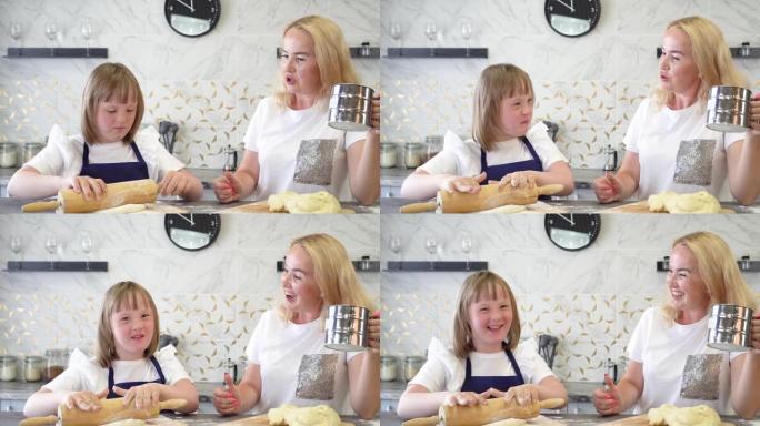 患有唐氏综合症的女孩和她迷人的母亲，在厨房里烤面团馅饼。国际唐氏综合症日概念。