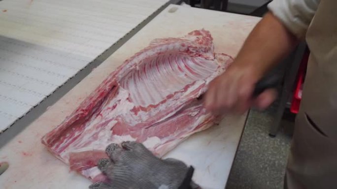 在肉类生产中分离肉类和排骨。肉厂工人在切肉。