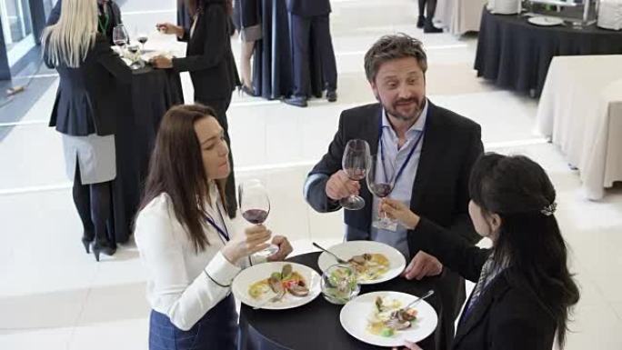 在会议中心的研讨会休息期间，三名同事用一杯葡萄酒吃午餐