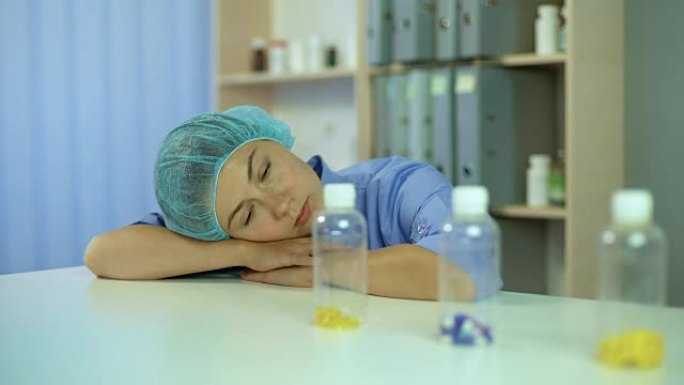 过度劳累的护士睡在桌子上，醒来并带着药瓶离开
