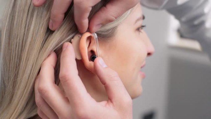 医生为一名女性患者安装助听器的前视图特写