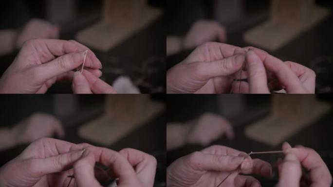 坦纳 (tanner) 的手将线拉入针头并打结。手工皮革制品的生产。爱好概念。慢动作。