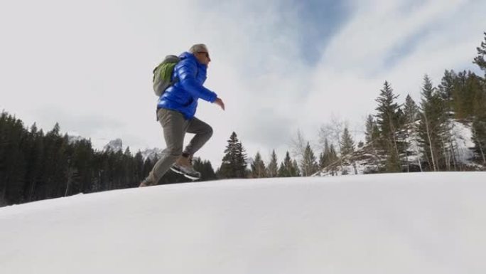 成熟的人沿着山脊徒步穿越积雪