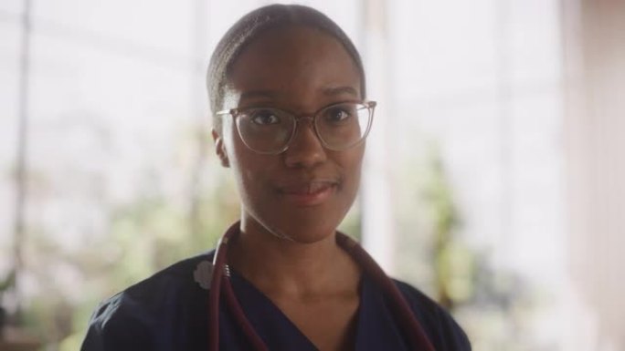一位黑人女性医疗保健专业人员的肖像，对着镜头摆姿势，微笑着看着镜头。非洲诊所医师戴眼镜，在医院办公室