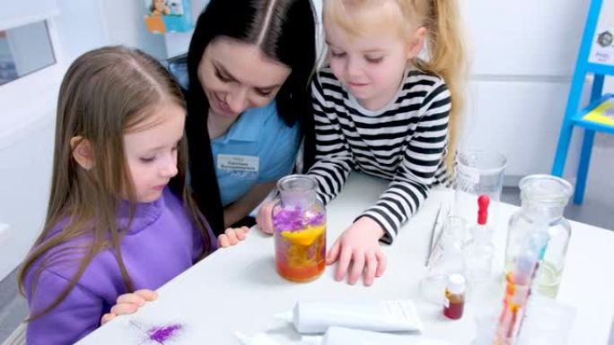 儿童化学实验室两个女孩医生向他们展示了有趣的研究一个女孩伤心又害怕第二个微笑她喜欢桌子上的工具玻璃烧