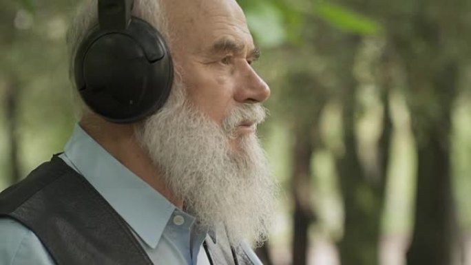 灰发老人戴着耳机听音乐