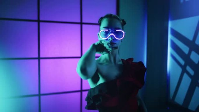 戴荧光眼镜的现代年轻女子在彩色霓虹灯背景上跳舞性感女士概念