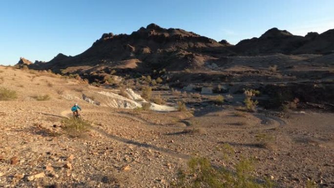 成熟女子在沙漠小径上骑电动自行车