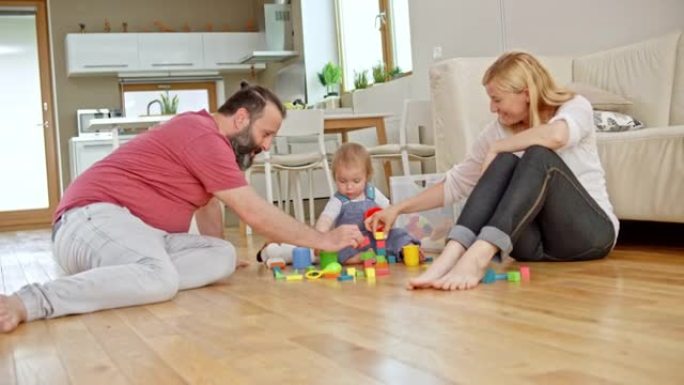 SLO MO妈妈和爸爸坐在地板上，和他们的男婴玩耍