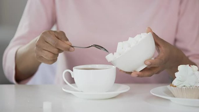 女人在茶杯中加入许多方糖，血糖问题和成瘾