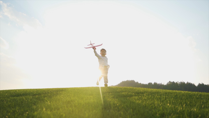 小男孩拿飞机模型草地奔跑梦想翅膀欢乐童年